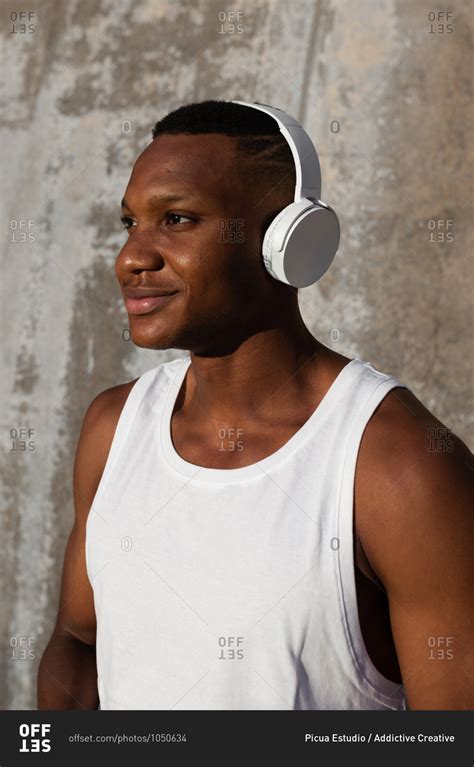 Cheerful African American Male In Wireless Headphones Listening To Songs While Training Outdoors