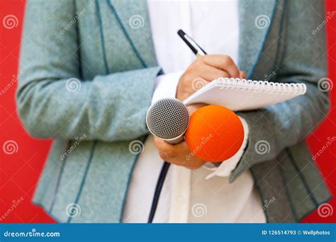 Journalist At News Conference Writing Notes Holding Microphone Stock