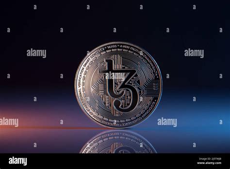 Tezos Xtz Cryptocurrency Physical Coin Placed On Reflective Surface And Lit With Orange And Blue