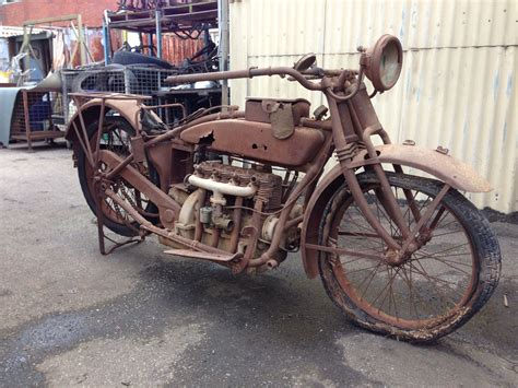 An Old Rusted Motorcycle Parked In Front Of A Building