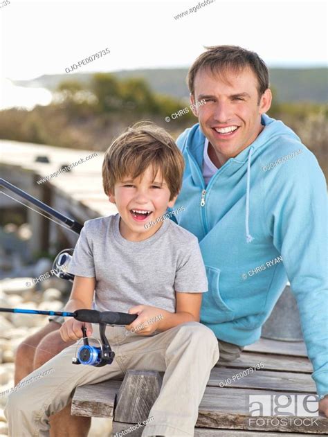 Portrait Of Smiling Father And Son Holding Fishing Rod Stock Photo