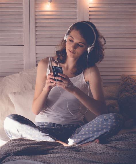 Young Woman Relaxing In Her Bed She Is Listening To Music Stock Photo