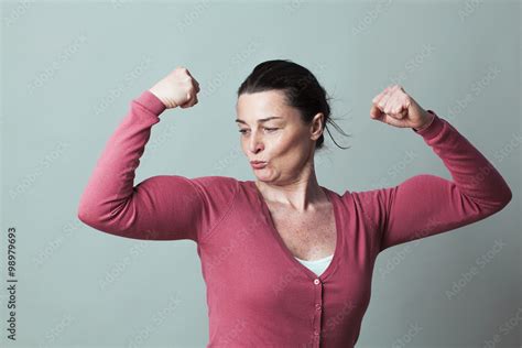 muscle concept proud beautiful 40s woman admiring her flexing muscles for metaphor of female
