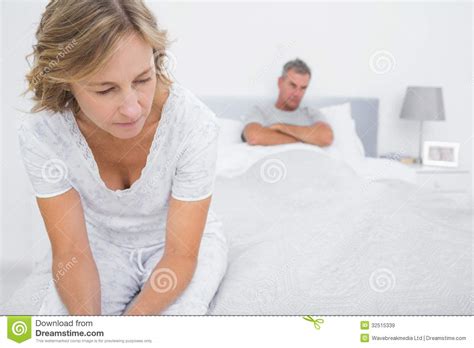 Couple Sitting On Opposite Ends Of Bed After A Fight Stock Image