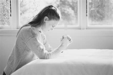 a woman kneeling in prayer by her bedside — photo — lightstock