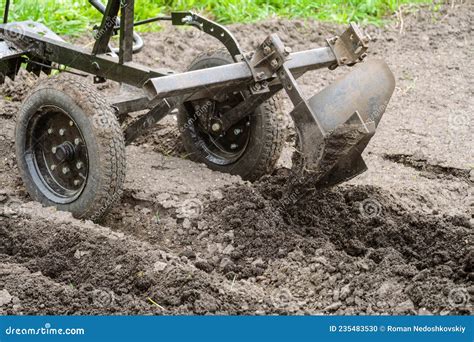 Cultivator With Plow Makes Furrow In Soil For Plantation Stock Photo
