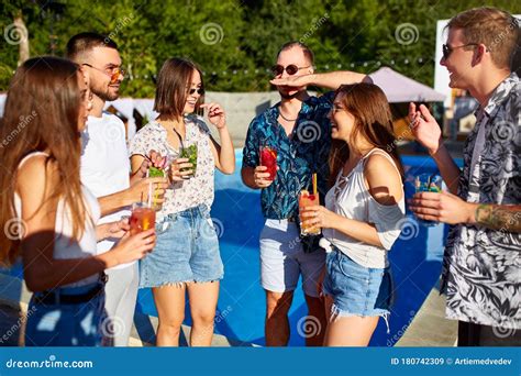 Group Of Friends Having Fun At Poolside Summer Party Clinking Glasses