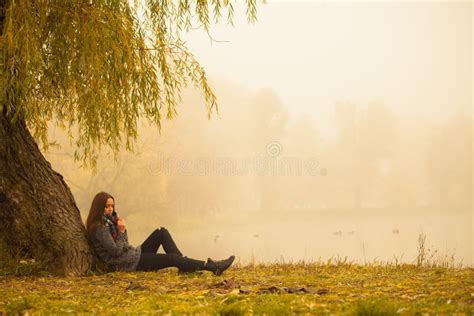 Lonely Woman Having Rest Under The Tree Near The Water In A Foggy