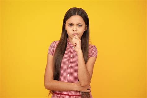 Premium Photo Smart Nerdy School Girl Touching Cheek And Thinking Against Yellow Background