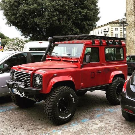 A Red Four Door Suv Parked Next To Other Cars
