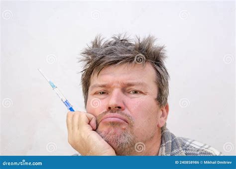 Portrait Of A Brooding Adult Male With A Blue Syringe Stock Photo