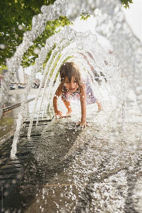 Girl Getting Wet While Passing Underneath Fountain In City Square By Stocksy Contributor Ibex