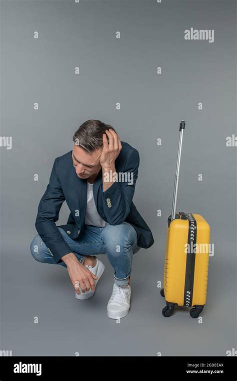 Sad Man Crouched Near His Suitcase Stock Photo Alamy