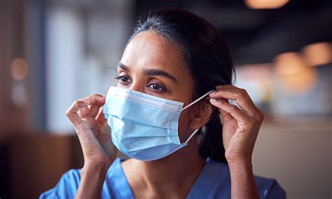Photo Of A Nurse Securing A Face Mask Behind Her Ear Withdrawing Face