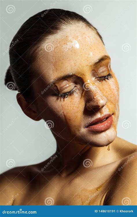 Portrait Of Happy Beautiful Young Brunette Woman With Freckles And Honey On Face With Closed