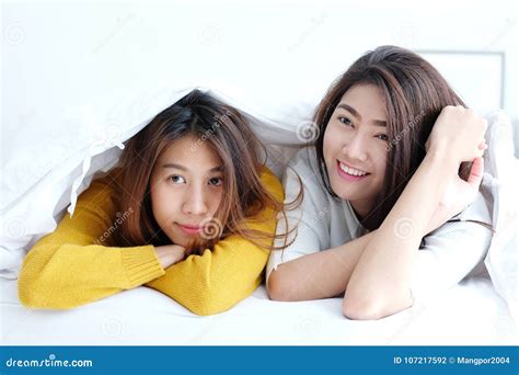 lgbt de jonge leuke lesbiennes die van azië en op wit bed liggen glimlachen aan stock foto