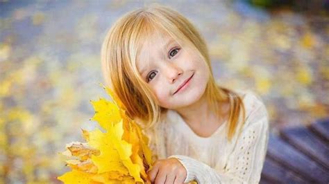 Smiley Cute Girl Is Holding Yellow Leaves With Hands