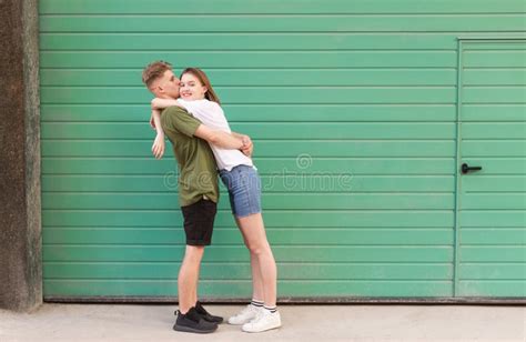 Amusing Couple Lovers Hugging And Kissing The Background Of A Green Wall On The Street Funny