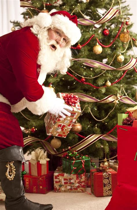 Miniature christmas tree and gifts under it stands near fireplace, two champagne glasses and gift boxes on fireplace. Should kids know the truth about Santa?