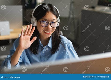 Korean Businesswoman Video Calling On Computer Waving Hello In Office