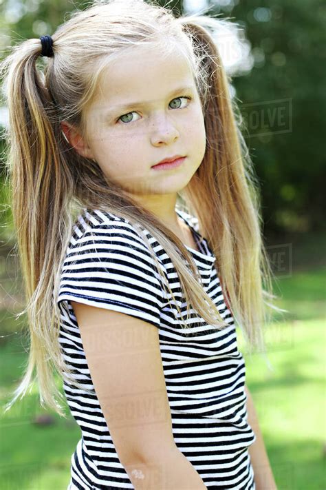 Serious Girl With Pigtails Standing In Field Stock Photo Dissolve