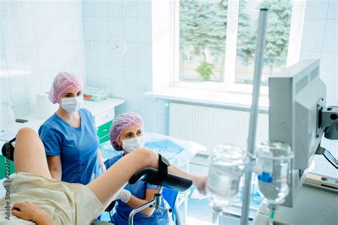 Female Gynecologist And Assistant In Mask And Hair Cap Working Unrecognizable Patient In