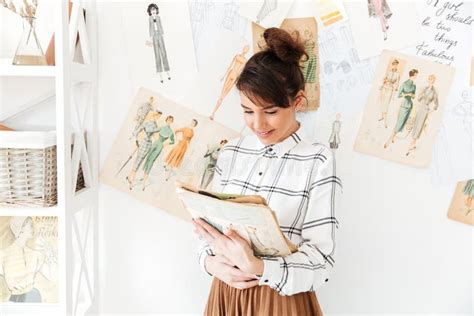 Woman Fashion Designer Holding Sketchbook While Standing At Her Studio