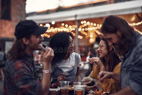 Cheerful Friends Chatting And Eating In Outdoor Cafe Stock Photo