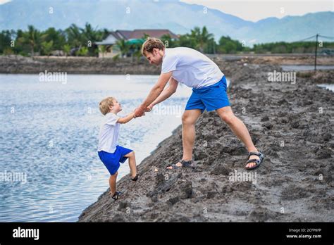 Dad helps son go down to lake water, explains safety rules. Family