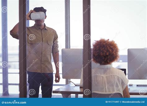 Businessman Wearing Vr Headset With Female Colleague In Office Stock