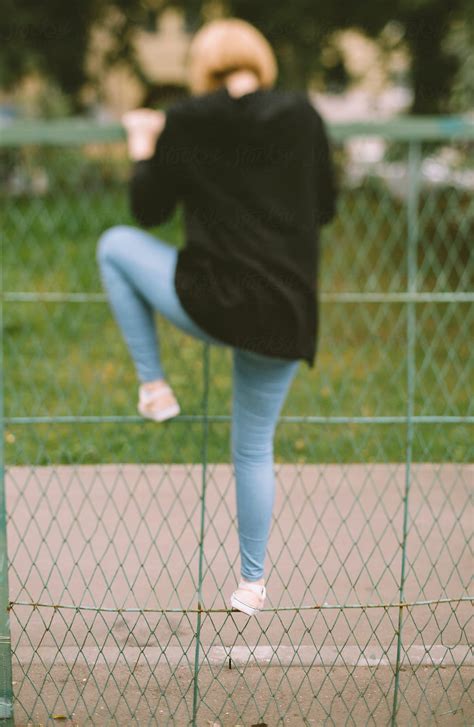 Teen Girl Climbing Over The Fence By Stocksy Contributor Alexey