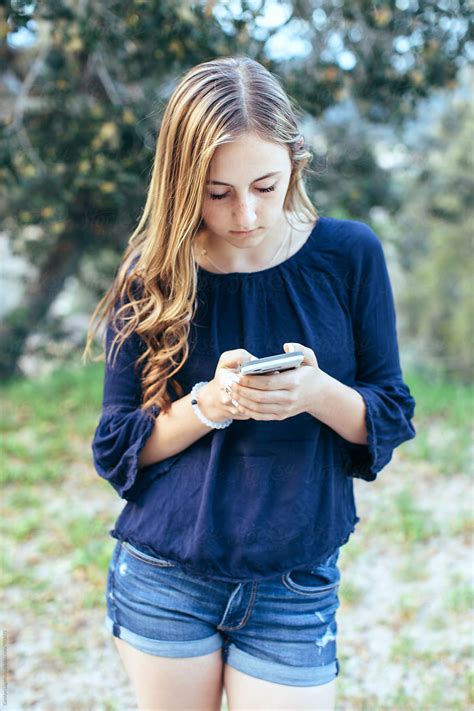 Teenage Girl In Shorts Texting On Her Phone By Carolyn Lagattuta