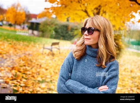Portrait Shot Of Confident Mature Woman Wearing Turtleneck Sweater And Sunglasses While Standing