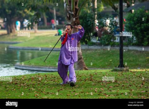 Thai Mature Man Undertaking Tai Chi Exercises With A Long Blade Sword In Lumpini Park Bangkok