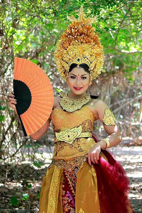A Woman Dressed In Traditional Thai Garb Holding An Orange Fan