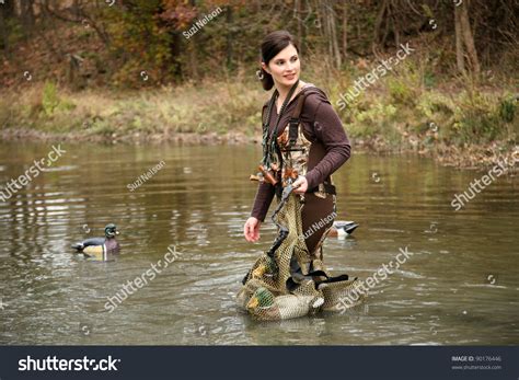 Woman Duck Hunter In Camo Waders In Pond With Decoys Bag Stock Photo