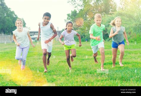 Five Smiling Kids Running And Laughing In Park Stock Photo Alamy
