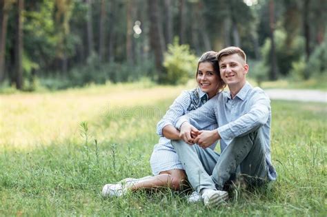 Outdoor Shot Of Young Happy Couple In Love Sitting On Grass On Nature
