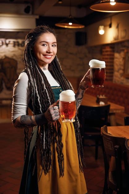 Garçonete Bonita Com Duas Canecas De Cerveja Na Mão Em Um Bar De Cerveja Foto Premium