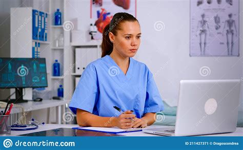 Medical Assistant Typing On Laptop And Taking Notes On Clipboard Stock