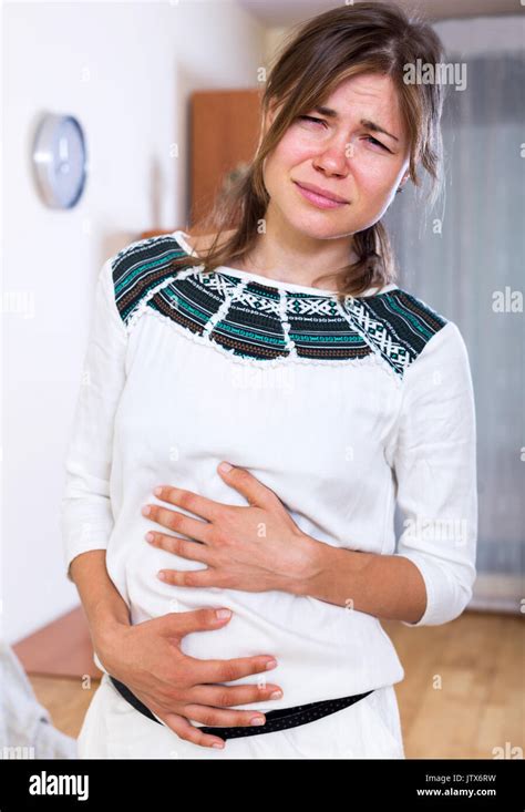 Portrait Young Woman With Abdominal Pains In Home Interior Stock Photo