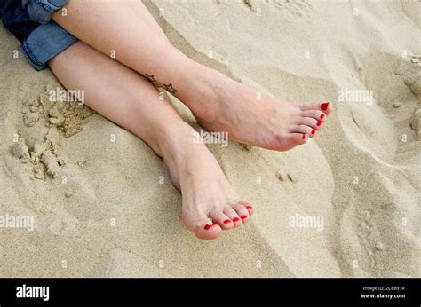 Female Feet With Red Nail Polish Lying In The Sand At The Beach Stock