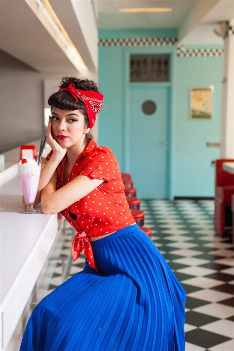 portrait of beautiful roackabilly woman with milkshake at retro diner restaurant by stocksy