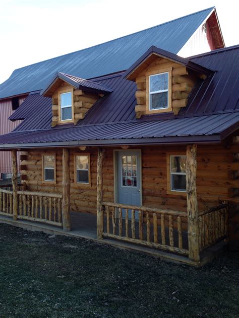 A Log Cabin With Metal Roofing And Wooden Railings