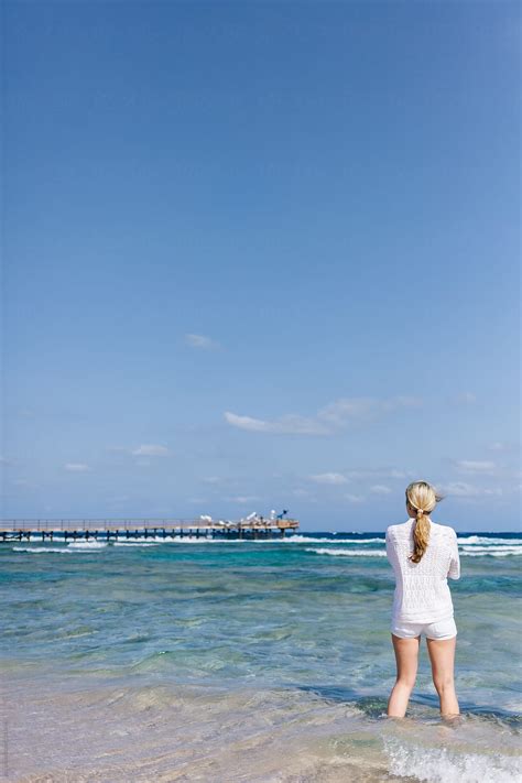 Young Anonymous Woman In White Outfit Standing On Beach Pier Looking At Sea By Stocksy