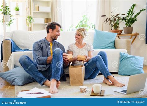 Pareja Feliz Sentada En El Suelo En Casa Comiendo Hamburguesas Imagen De Archivo Imagen De