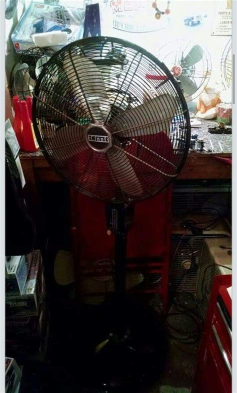 An Old Fan Sitting On Top Of A Table Next To A Red Cabinet And Other