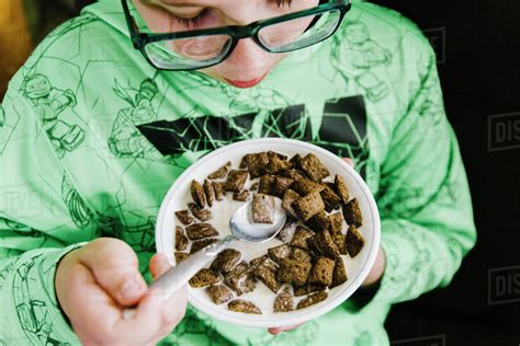 Boy Eating Chocolate Cereal From A White Bowl Stock Photo Dissolve