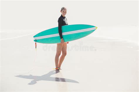 woman in wetsuit holding a surfboard on the beach stock image image of person looking 68289883