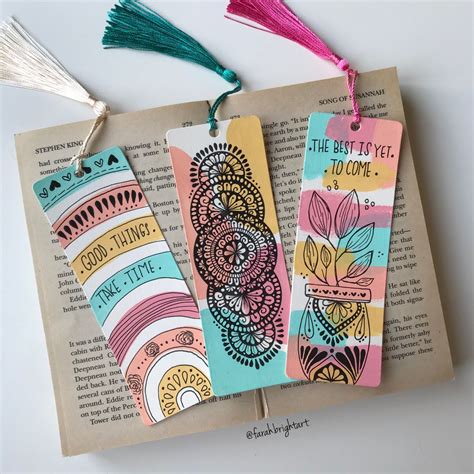 Three Bookmarks With Tassels On Top Of An Open Book